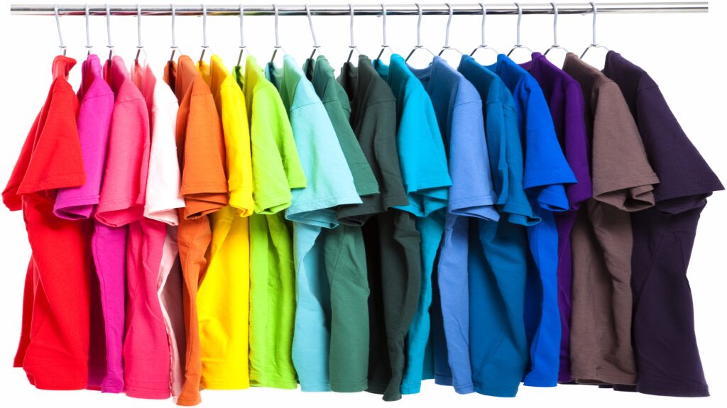 A row of colorful t-shirts hanging on a rack, arranged by color.